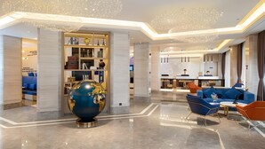 A modern hotel lobby with a globe centerpiece, a seating area with blue sofas, and a bar. - Kyriad Marvelous Hotel Shenzhen Nanlian Metro Station (Shenzhen)