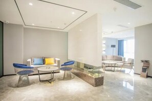 A modern hotel room with a sofa, two chairs, a coffee table, and a glass partition. - 7 Days Premium Hotel (Chongqing)