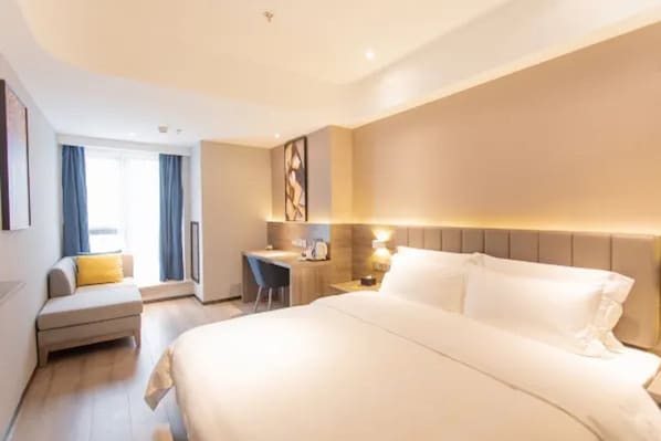 A hotel room with a large bed, a desk, a chair, and a sofa. - 7 Days Premium Hotel (Chongqing)