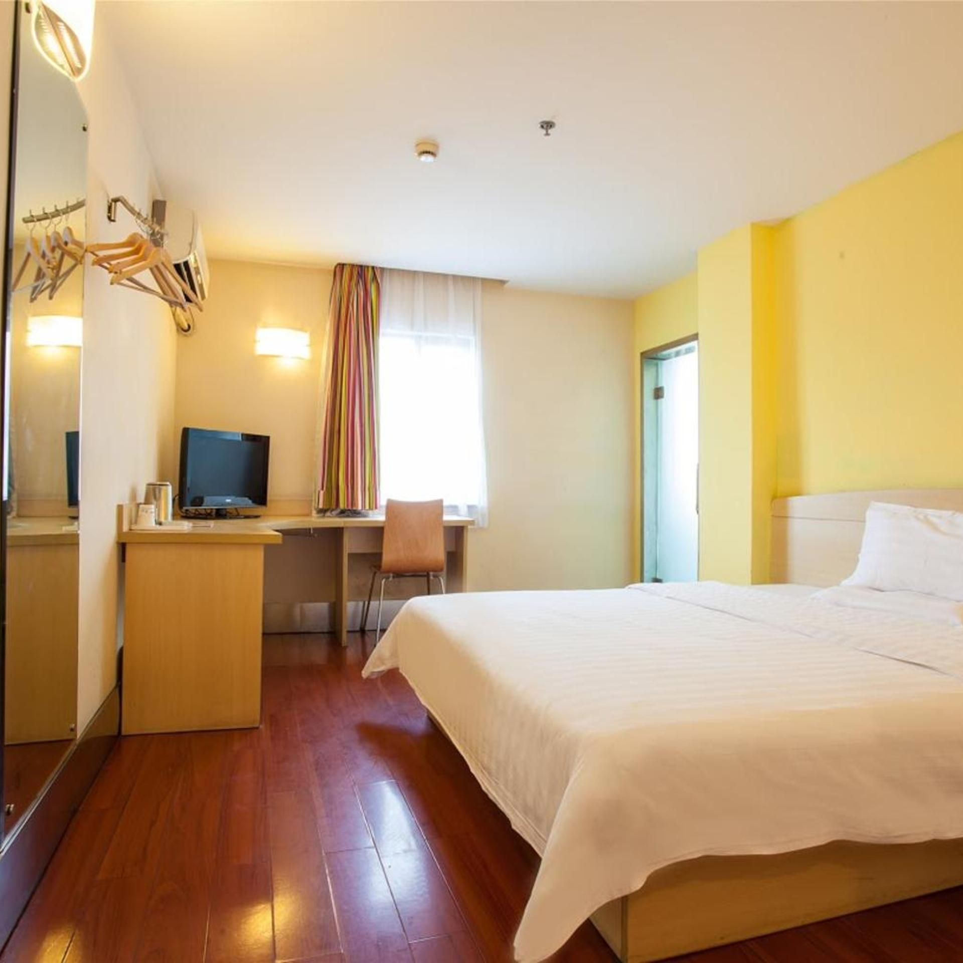 Ein Hotelzimmer mit Bett, Schreibtisch, Stuhl, Fernseher und Spiegel.