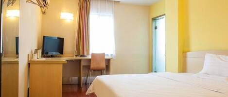 Ein Hotelzimmer mit Bett, Schreibtisch, Stuhl, Fernseher und Spiegel.