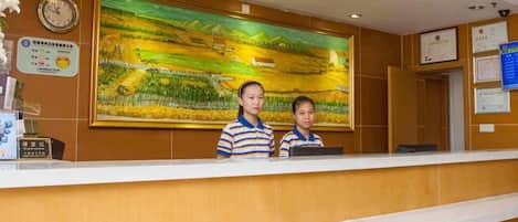 A reception desk with a large landscape painting above it, a clock, and various certificates on the wall.