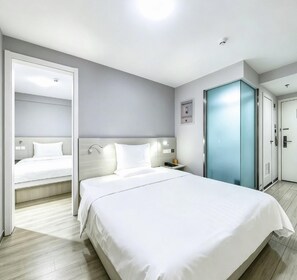 A hotel room with a large bed, a bedside table, a nightstand, a wardrobe, and a door. - 7 Days Inn (Beijing)