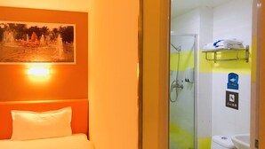 Ett hotellrum med en säng, en dusch och ett handfat.