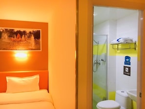 Una camera d'albergo con un letto, una doccia e un lavandino.