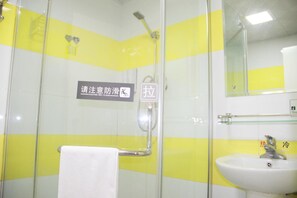 Un bagno con piastrelle gialle e bianche, box doccia in vetro, lavandino e specchio.