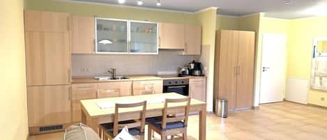 Une cuisine de taille réduite comprenant une table et des chaises, un canapé et une poubelle.