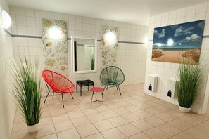 A room with a tiled floor, a window, two chairs, a small table, and a potted plant. - Queen Augusta Dune Residence 2 (Ostseebad Binz)