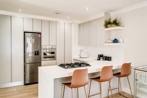 Een moderne keuken met een centraal eiland, roestvrijstalen apparatuur en een glazen overkapping.