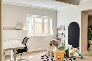 A room with a white desk, a chair, a bookshelf, a toy, and a large black arch on the wall. - Green Point 4 Bed Family Home w Pool Happy House (Cape Town)