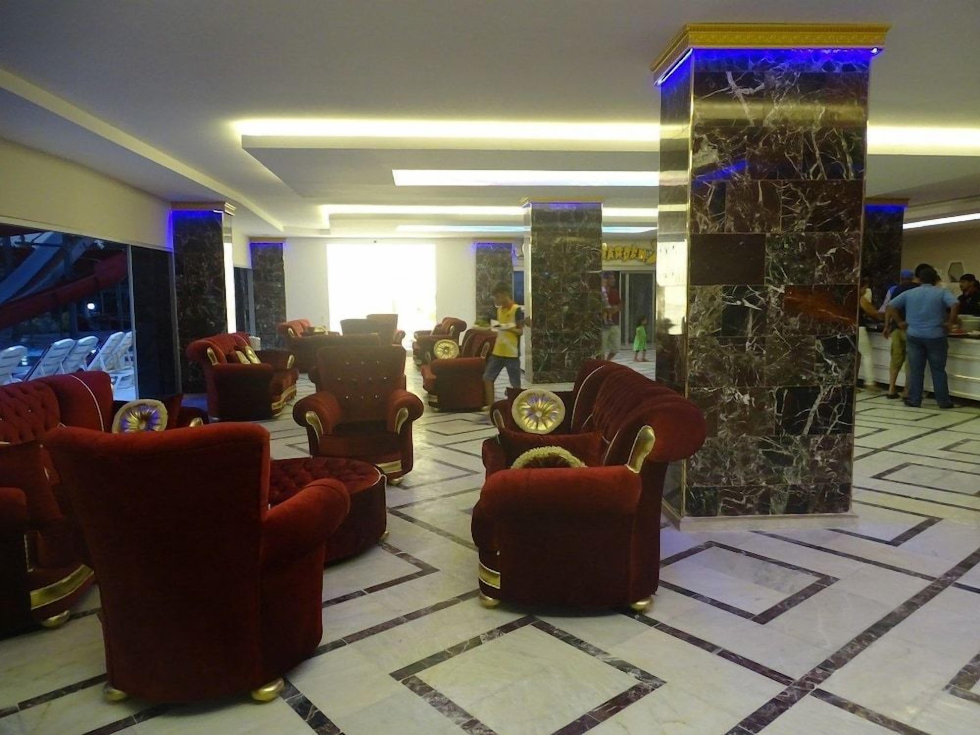 A lobby with red upholstered armchairs, a marble column, and a reception area.
