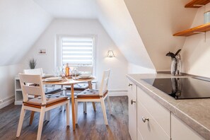 A dining area with a round table, chairs, and a window with blinds. - TOPP in the Captain's House Ostseerose (Travemünde)