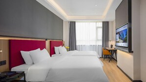 A hotel room with a large bed, a desk, a chair, and a television. - Campanile (Shenzhen)