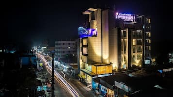 A multi-story hotel with a prominent sign reading 'Grand Palace' at night.
