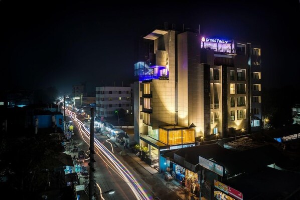 A multi-story hotel with a prominent sign reading 'Grand Palace' at night.