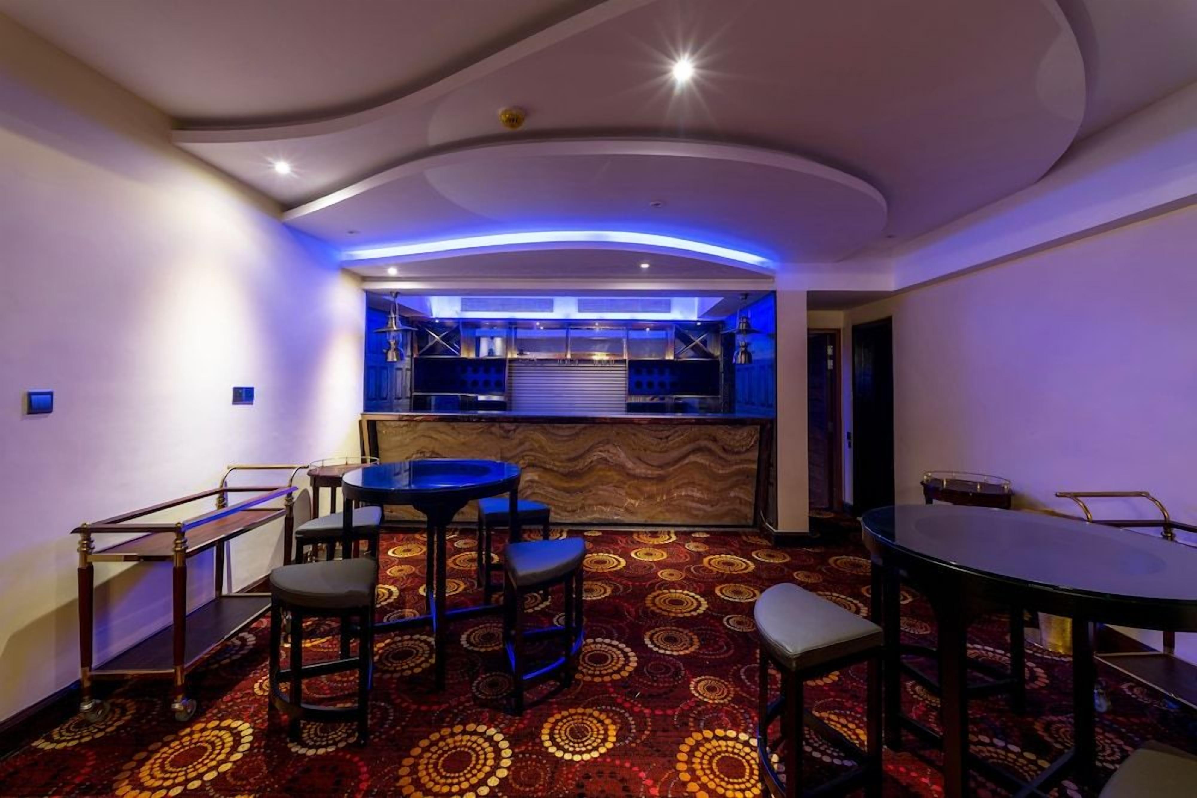 A bar area with a counter, stools, and a patterned carpet.