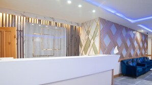 A reception area with a white reception desk, blue seating, and patterned walls. - Legend Hotel Kalam (Swat)