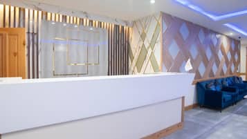 A reception area with a white reception desk, blue seating, and patterned walls.