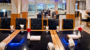 A restaurant with tables set for dining, featuring a modern design with wooden accents and blue lighting. - Legend Hotel Kalam (Swat)