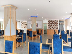Un comedor moderno con sillas tapizadas en azul, mesas de madera y paneles decorativos en las paredes.