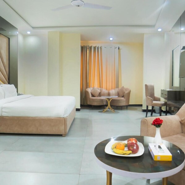 A hotel room with a bed, a sofa, a coffee table with fruit, and a TV. - Legend Hotel Kalam (Swat)