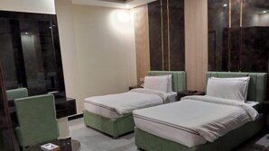 A hotel room with two single beds, a sofa bed, a small table, and a TV. - Legend Hotel Kalam (Swat)