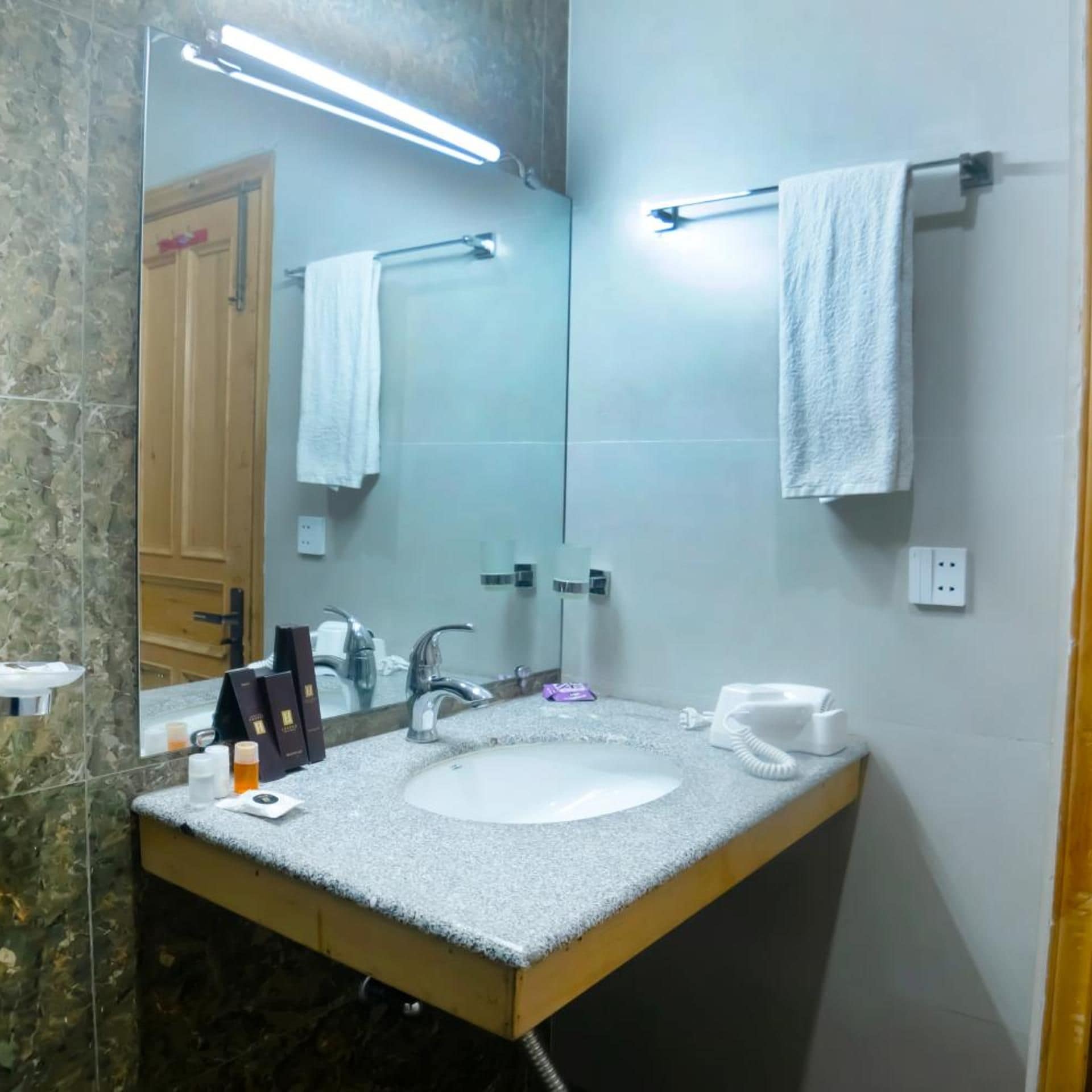 A bathroom with a white sink, a mirror, a towel rack, and a telephone.