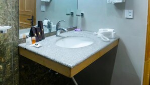 A bathroom with a white sink, a mirror, a towel rack, and a telephone. - Legend Hotel Kalam (Swat)