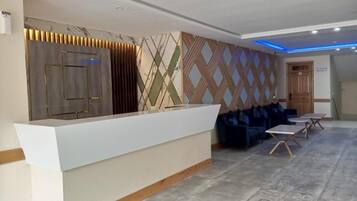 A reception area with a white counter, patterned wall, and blue seating.