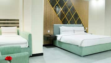 A hotel room with two beds, a nightstand, a small table with a vase, and a decorative wall panel.