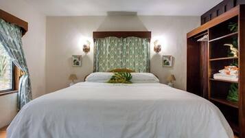 A hotel room with a large bed, two bedside lamps, a wooden wardrobe, and a window with curtains.