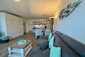 Ein modernes Wohnzimmer mit einer Couch, einem Couchtisch und einem Essbereich mit Stühlen.