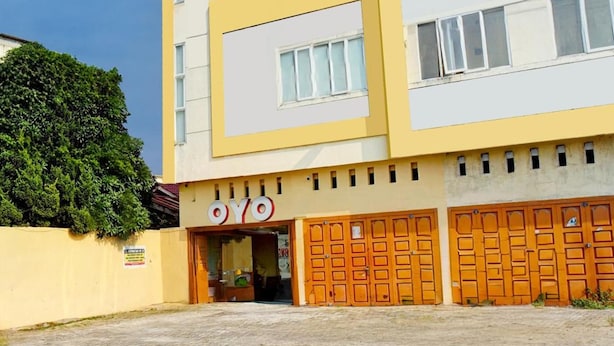 A multi-story building with a yellow facade and a sign that reads 'OYO'. - Super OYO 93930 The Sunny Inn (Medan)