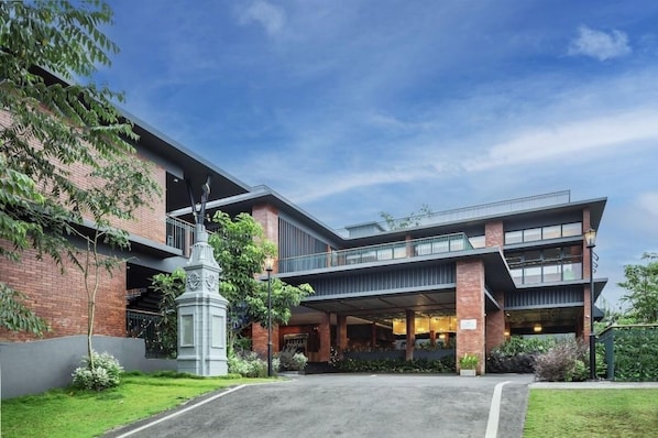 Un edificio moderno con fachada de ladrillo, entrada central y un vestíbulo cubierto.
