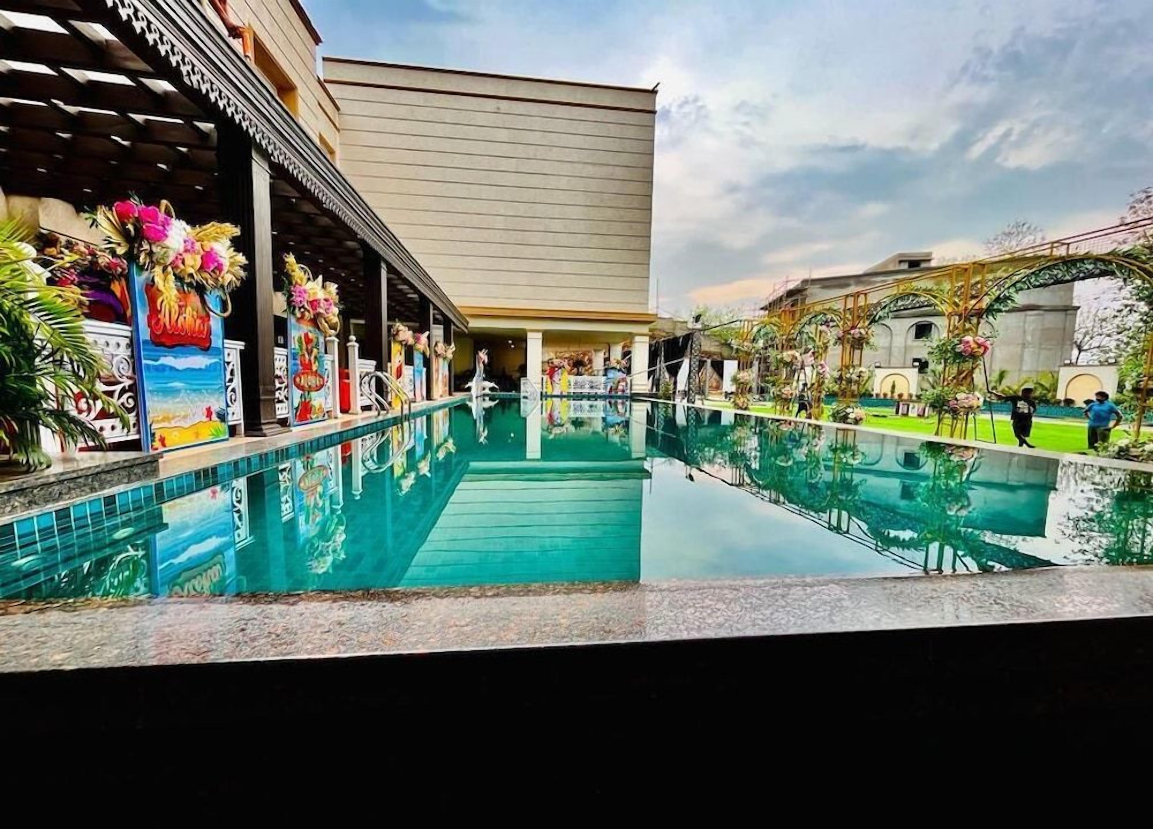A hotel pool area with a clear view of the pool, a covered walkway, and a building facade.