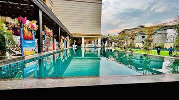 A hotel pool area with a clear view of the pool, a covered walkway, and a building facade.
