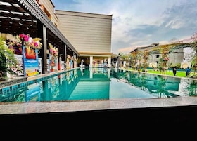 Zona de piscina de hotel con vista despejada, una galería techada y fachada de edificio.