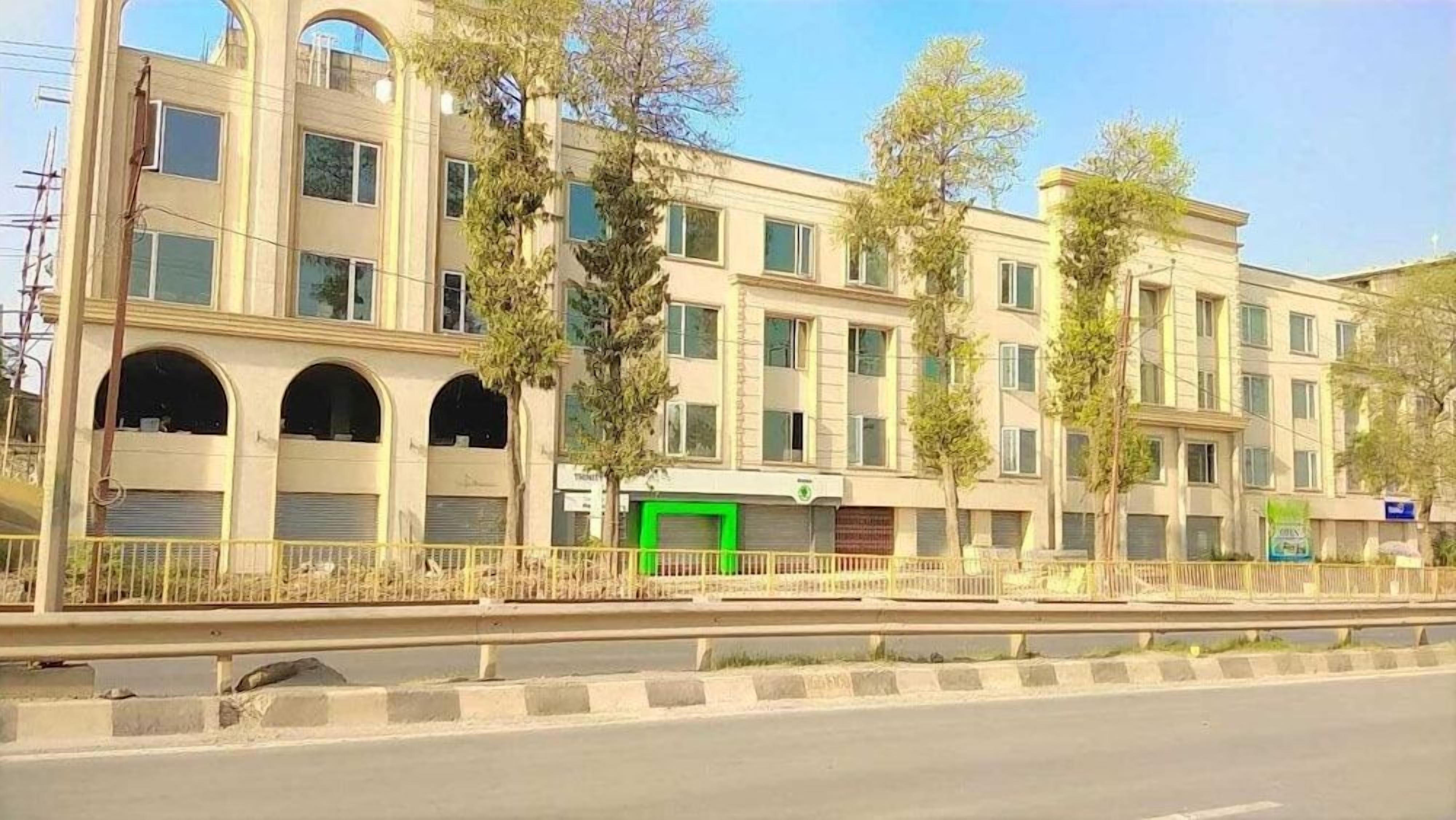 A multi-story building with a flat facade, large windows, and a green door.