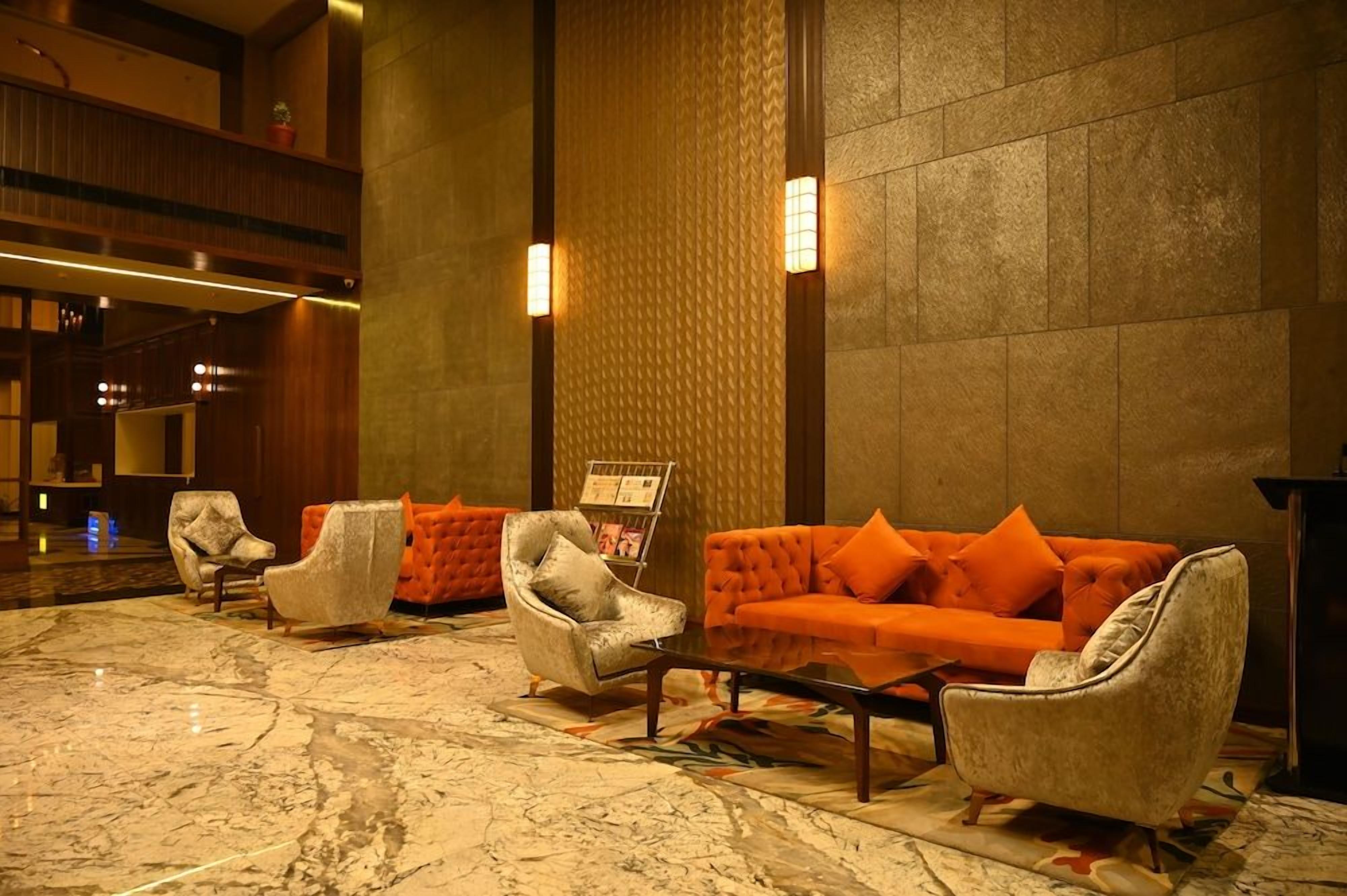 A lobby with a marble floor, seating area with armchairs and a sofa, and a reception desk.