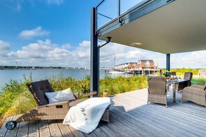 En terrass med utemöbler och utsikt över en vattenyta och en småbåtshamn.