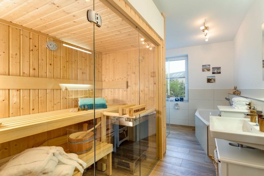Un sauna avec des murs en bois et une paroi en verre, un banc et un autre banc avec une serviette.