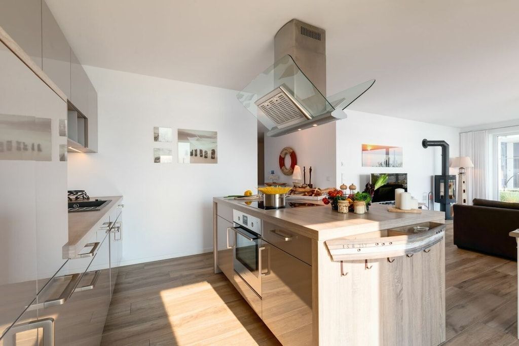 A modern kitchen with a central island, built-in oven, and stainless steel appliances.