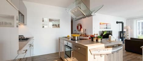 A modern kitchen with a central island, built-in oven, and stainless steel appliances.