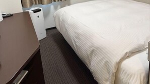 A hotel room with a bed, a desk, a flat-screen TV mounted on the wall, and a window with curtains. - Hotel Glany's Kumagayaekimae (Kumagaya)