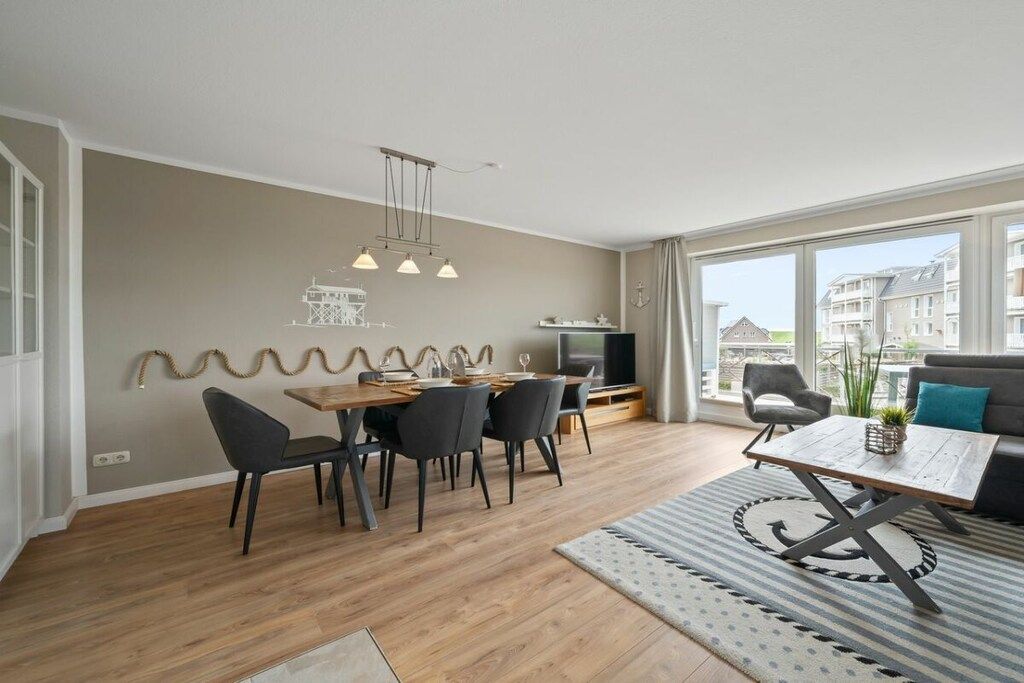 Un salon moderne avec un coin repas, de grandes fenêtres et une vue sur les immebles.