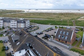 A coastal residential area with multi-story buildings, a roundabout, and a beach in the background. - Utholm 4a - Big Breeze (St. Peter-Ording)