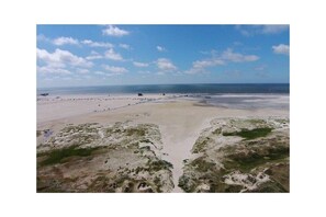 A coastal landscape with a sandy beach, a clear sky, and a distant view of the ocean. - Utholm 4a - Big Breeze (St. Peter-Ording)