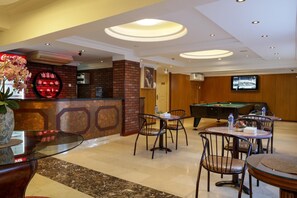 Un hall d’hôtel comprenant une table de billard, un espace salon et un comptoir d’accueil.