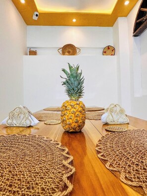 Ein Konferenzraum mit einem Holztisch, gewebten Untersetzern und einer Ananas als Mittelstück.