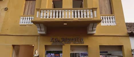 A two-story building with a commercial ground floor, a balcony, and a sign indicating a commercial center.